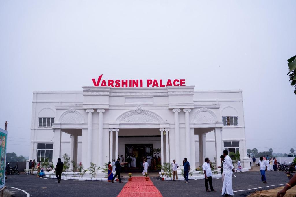 a large white building with people walking in front of it at Varshini Palace 