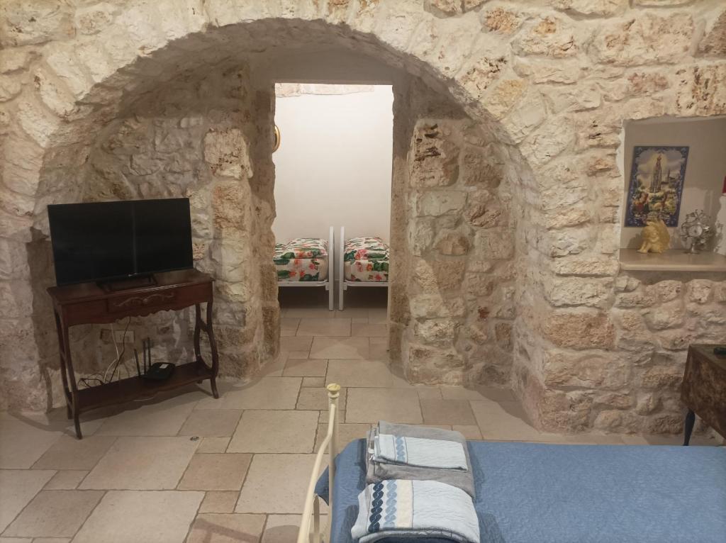 a room with a stone wall with a tv and a fireplace at Dovì Casa Vacanze in Carovigno