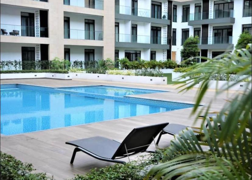 einen Pool mit einem Liegestuhl neben einem Gebäude in der Unterkunft Splendid Apartments - Embassy Gardens in Accra