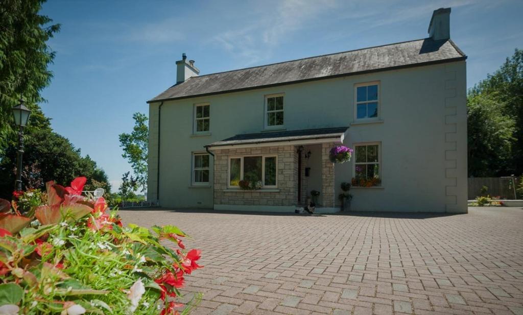 a large white house with a brick driveway at Grey Gables Farmhouse B&B in Inishannon