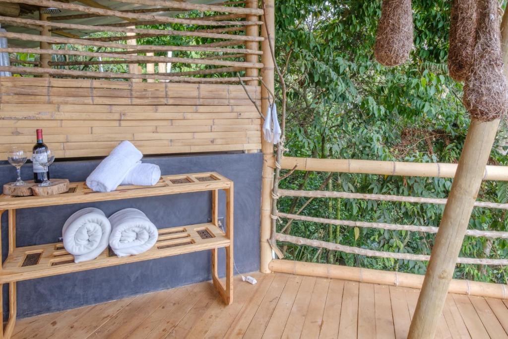 un porche con una mesa con toallas y un árbol en Tabatinga, Hermosa Cabaña Privada en Reserva Natural - Cali Valle del Cauca, en Cali