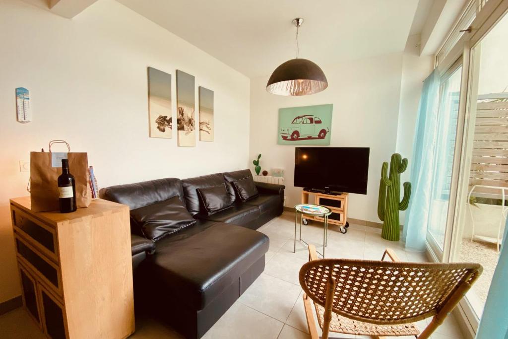 - un salon avec un canapé en cuir noir et une télévision dans l'établissement Escapade au Soleil B002 Appartement 2 chambres dans résidence sur la plage, au Grau-du-Roi