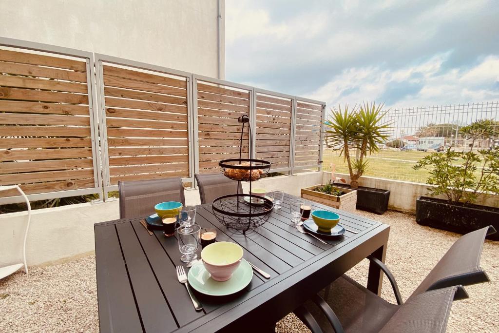 une table avec des bols et des tasses sur un balcon dans l&#39;établissement Escapade au Soleil B002, au Grau-du-Roi