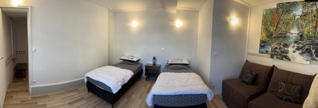 2 camas en una habitación con sofá en Le Bellagio, en Saint-Éloy-les-Mines