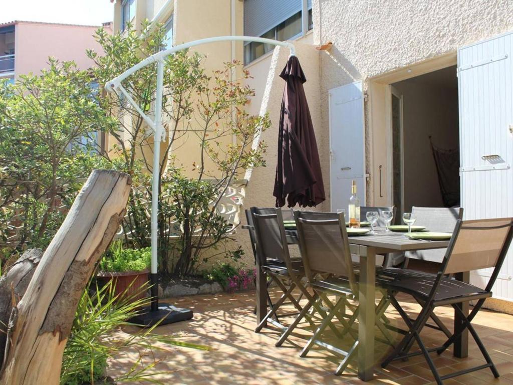 un patio avec une table, des chaises et un parasol dans l'établissement Maison Familiale 2 Étoiles à 150m de la Plage avec Terrasse, Jardin et Parking Privé - FR-1-229C-673, à Port-la-Nouvelle