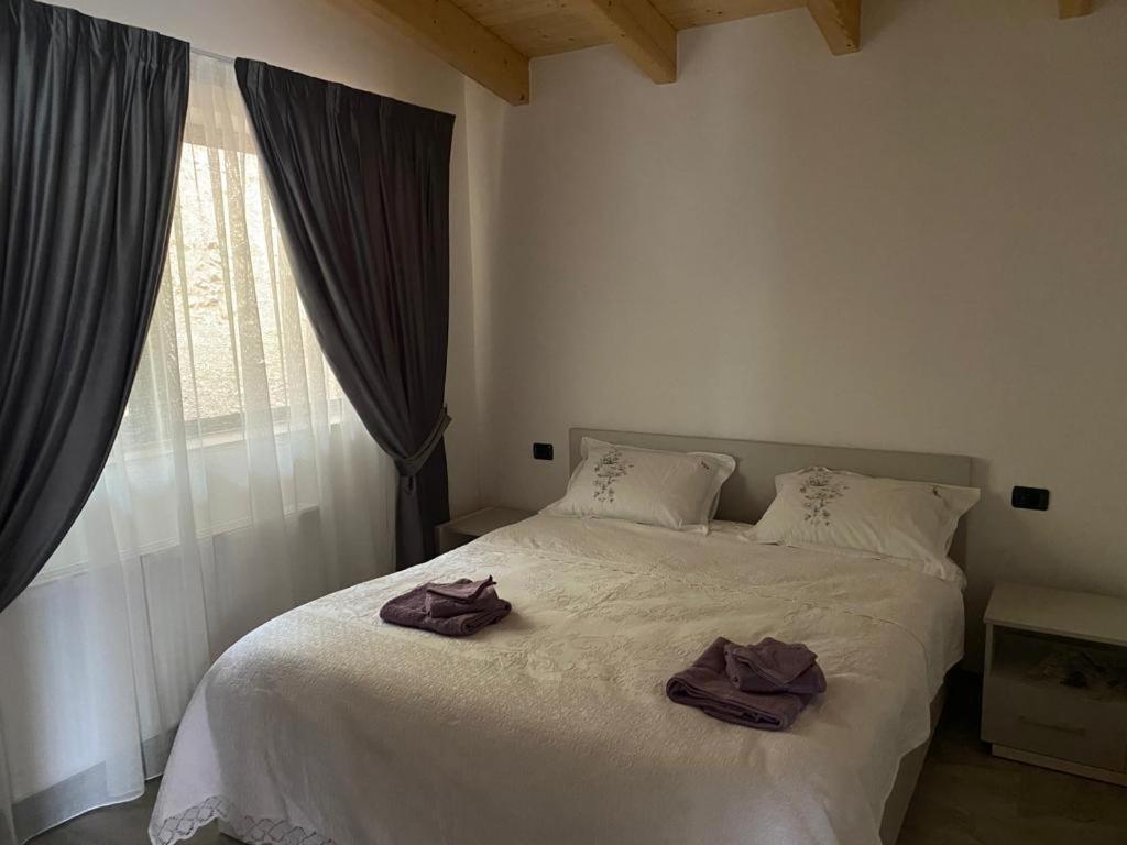 a bedroom with a white bed with two towels on it at Cabanele Olena in Borsa