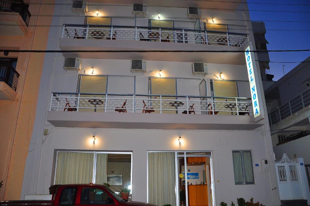 a white building with a balcony with lights on it at Nora Hotel in Sitia