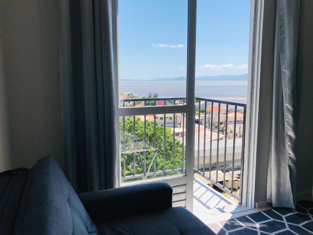 sala de estar con vistas a un balcón en Apto Beira Mar Grande Floripa, en Palhoça