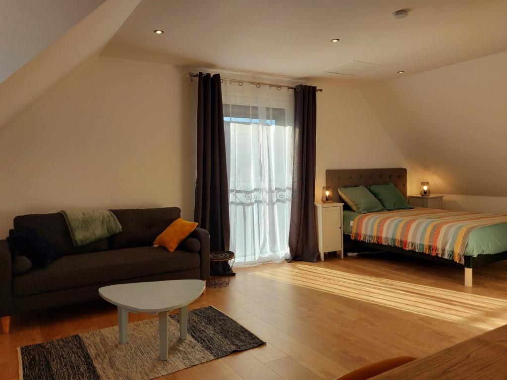 ein Wohnzimmer mit einem Sofa und einem Bett in der Unterkunft La Chambre du Valois in Cuvergnon