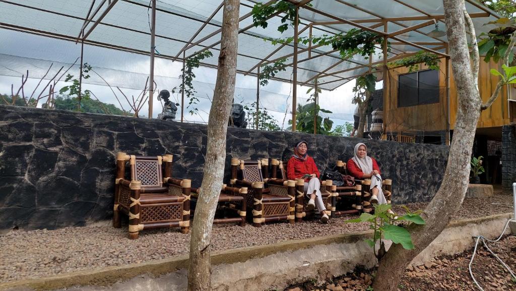 dos personas sentadas en un banco en un zoológico en Delta Island Camping Ground en Sumedang