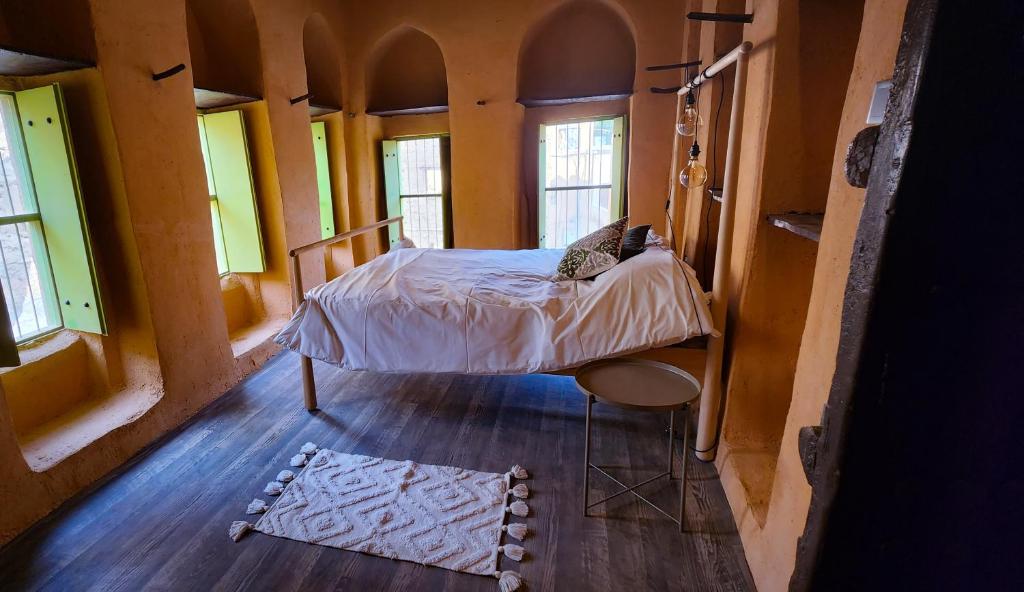 a bedroom with a bed in a room with windows at Bait Al Aali Guesthouse in Al Ḩamrāʼ