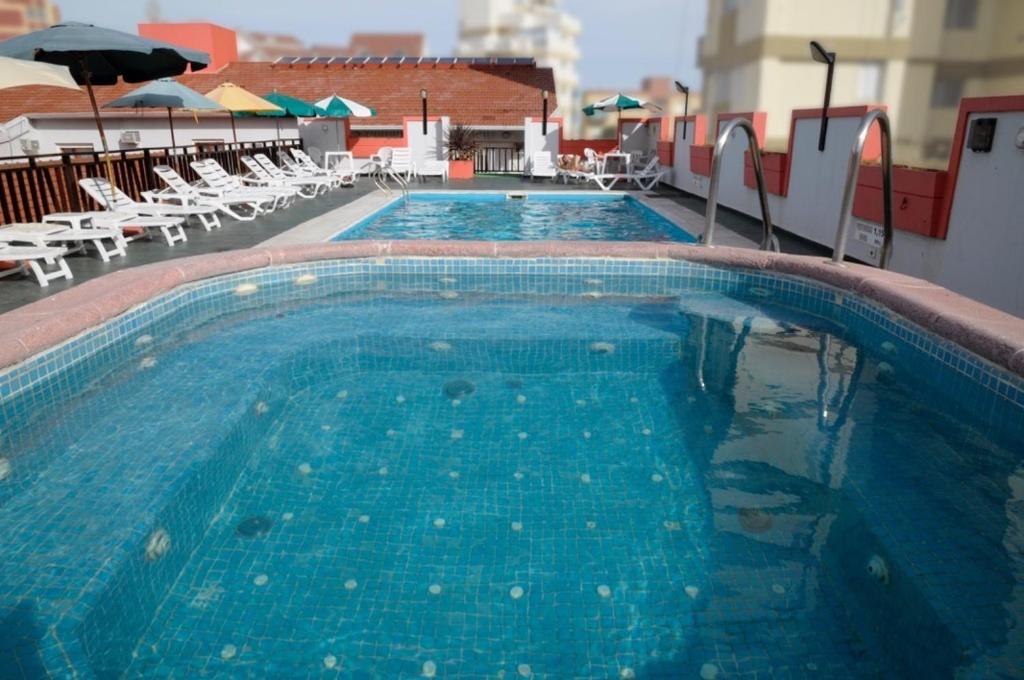 ビージャ・ヘセルにあるHosteria San Marcosの大きなスイミングプール(椅子、パラソル付)