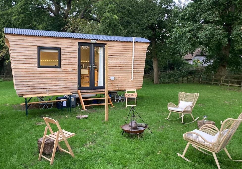 a small wooden cabin with chairs and a table at Aspen Leaves: The perfect farm retreat in Graffham