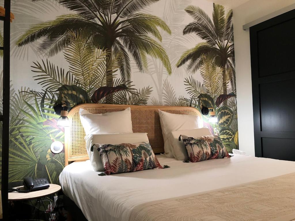 a bedroom with a bed with palm trees on the wall at Contact Hôtel Lunotel Saint Lô in Saint Lo