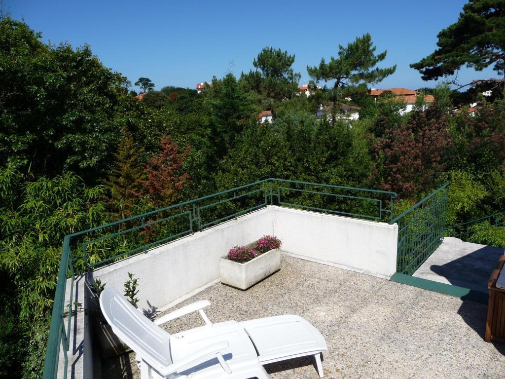 a balcony with two white chairs and a flower pot at Appartement Ranavalo Pays Basque in Anglet