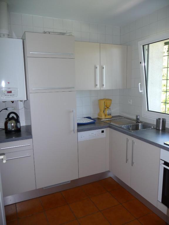 a kitchen with white cabinets and a sink and a window at Appartement Ranavalo Pays Basque in Anglet