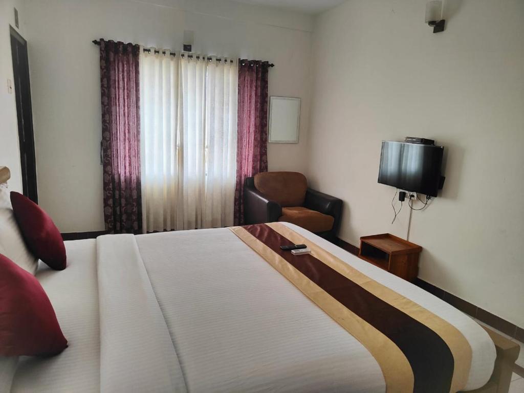 um quarto com uma cama, uma cadeira e uma televisão em Kapsstone HOMESTAY- Apartments &Rooms near APOLLO &SHANKARA NETHRALAYA HOSPITALS -Greams Road em Chennai