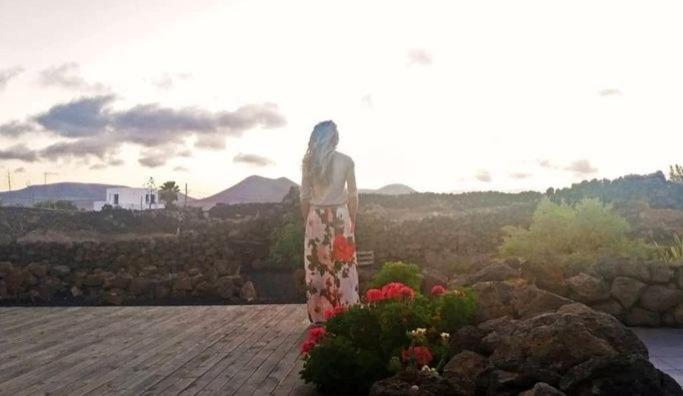 a woman in a dress standing next to flowers at Lajares Villa y estudios Art Lab Fuerteventura in Lajares