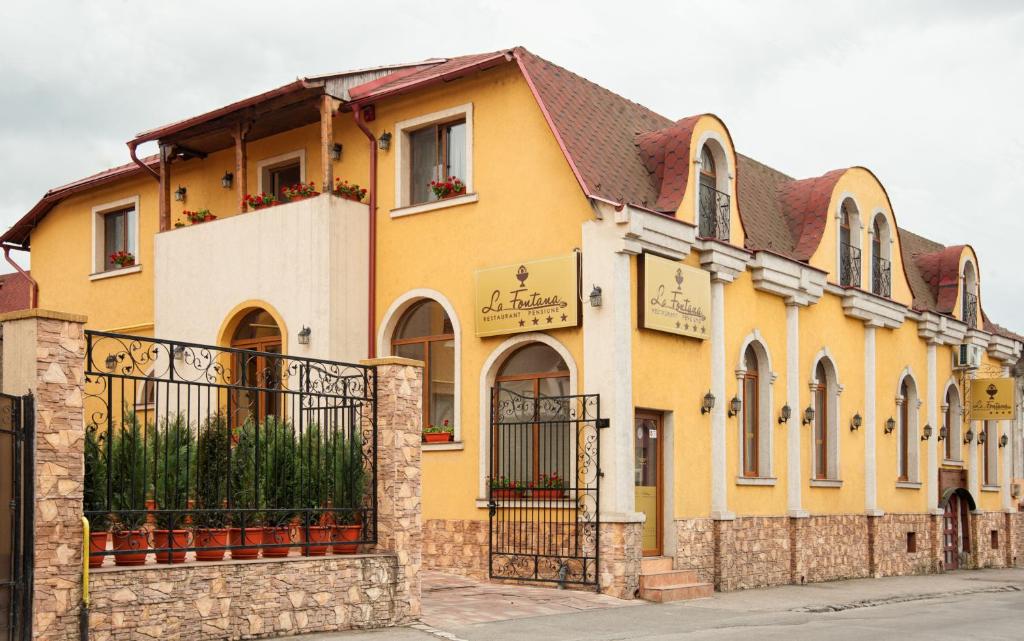 um edifício amarelo com um portão em frente em Pension La Fontana em Baia Mare