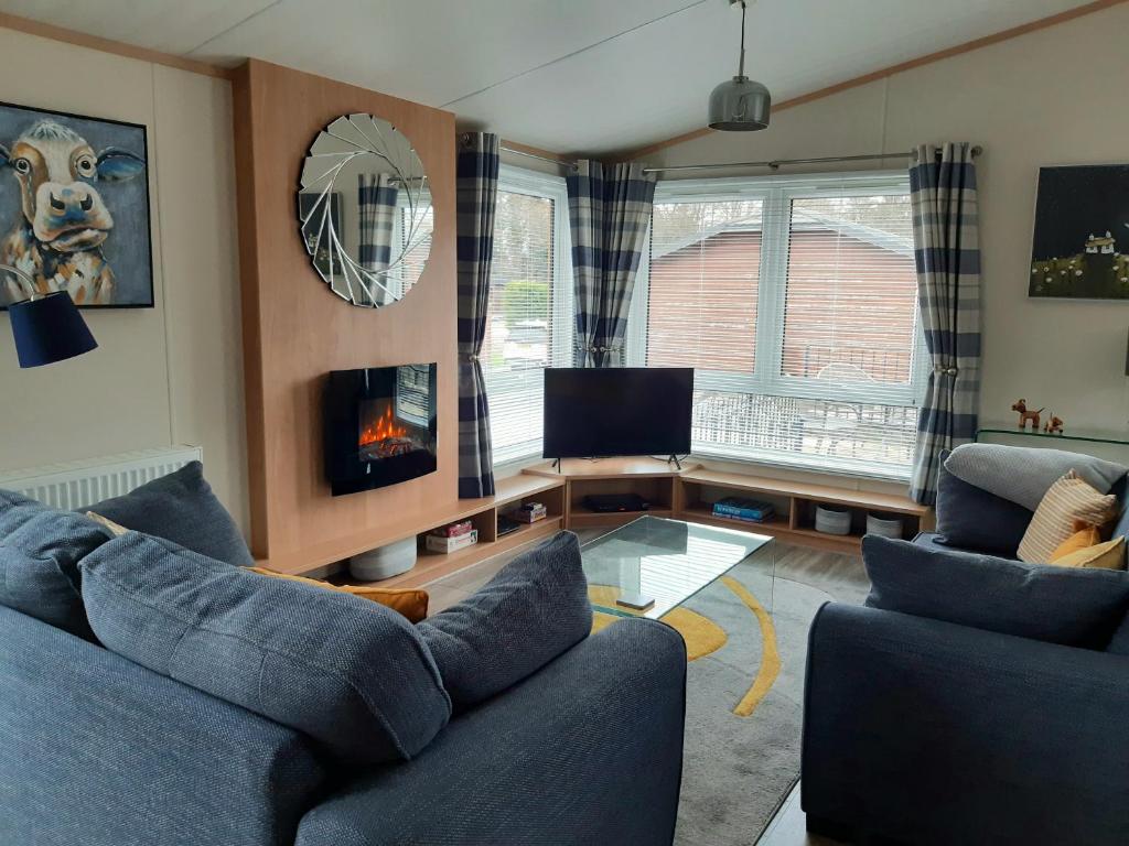 ein Wohnzimmer mit 2 blauen Sofas und einem Kamin in der Unterkunft Sycamore Lodge Auchterarder in Auchterarder