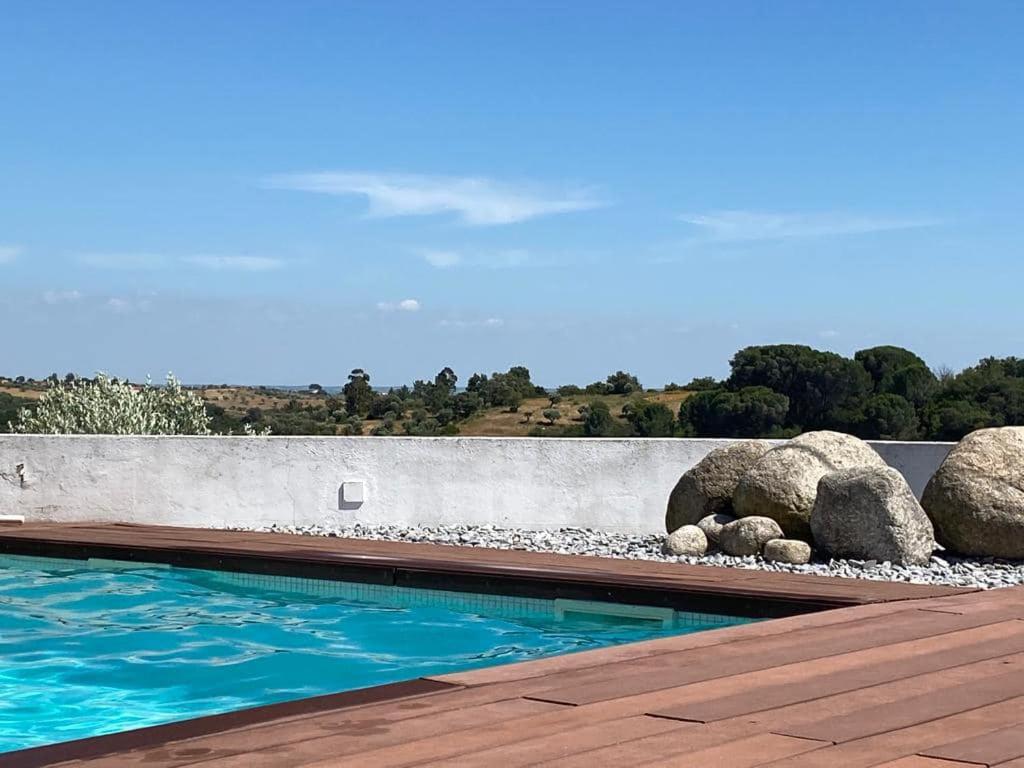 a swimming pool with rocks next to a wall at Casinha da Aldeia - country house with swimming pool in Santarém