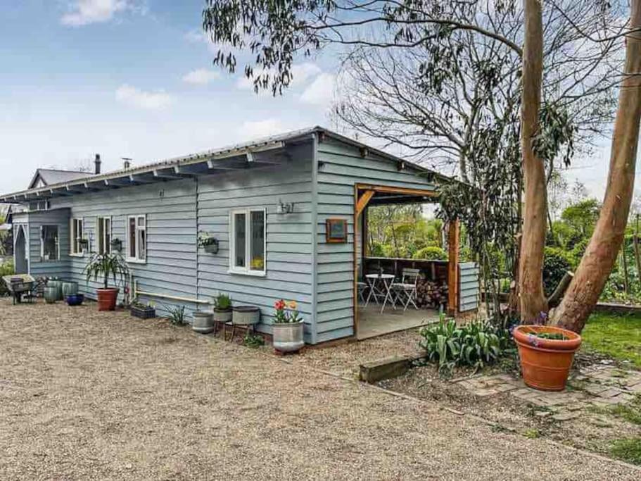 ein kleines blaues Haus mit einer Veranda und einer Terrasse in der Unterkunft The Nutshell. Rural retreat in Pluckley