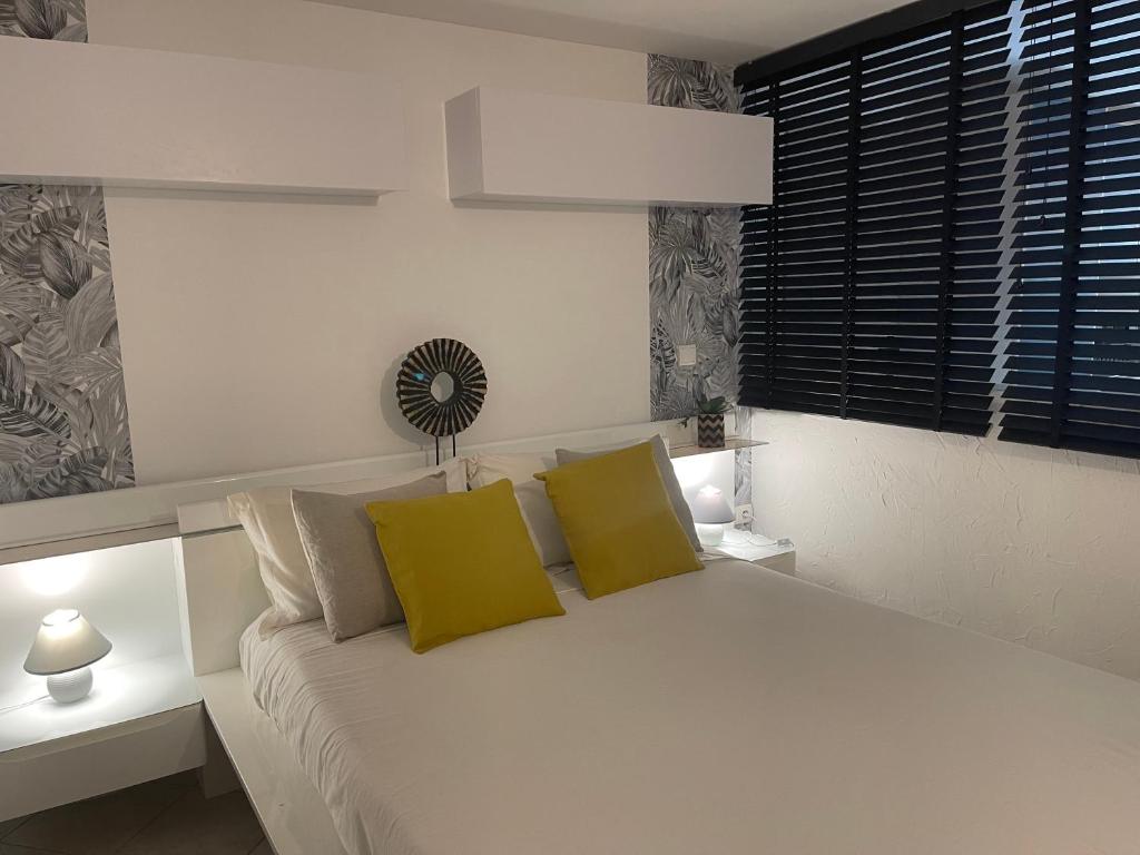 a bedroom with a white bed with two yellow pillows at bas de Villa "Le Tiste" in Valensole