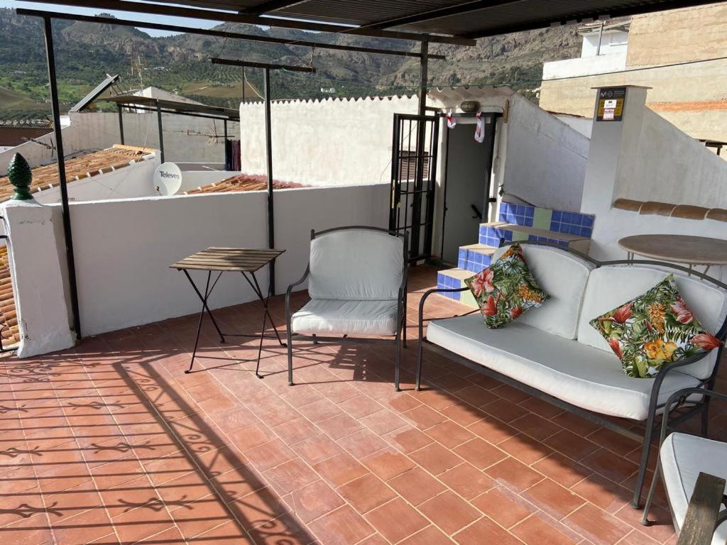 een patio met een bank, 2 stoelen en een tafel bij Casa Alora in Alora