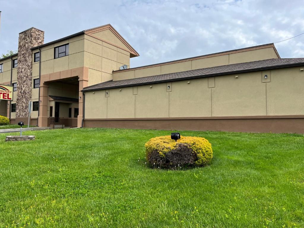 a bush in the grass in front of a building at Gallery Holiday Motel in South Amboy