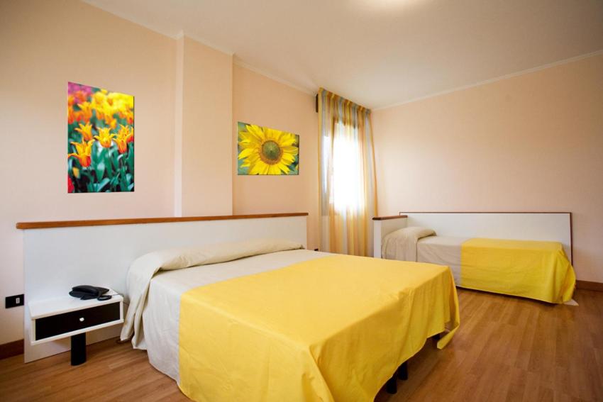 ポルト・トッレにあるHotel Ristorante Klausのホテルルーム 黄色いシーツ付きのベッド2台付