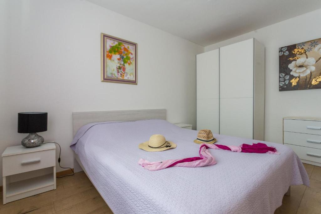 a bedroom with a bed with two hats on it at Apartments Tomas in Dubrovnik