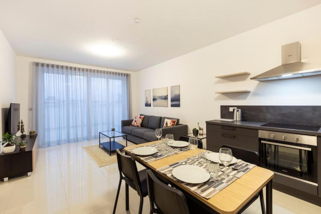 Beautiful Central Penthouse 1BR في Taʼ Xbiex: مطبخ وغرفة معيشة مع طاولة وكراسي
