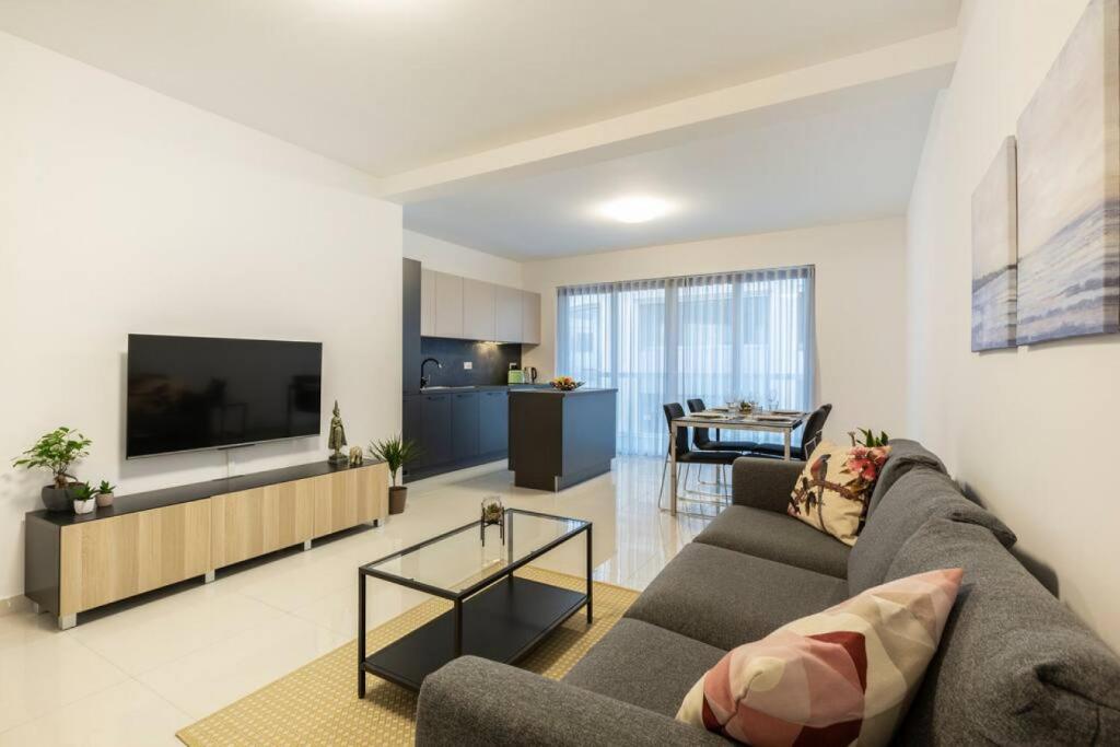ein Wohnzimmer mit einem Sofa und einem Flachbild-TV in der Unterkunft Beautiful Modern Central 2BR Apt 1 in Taʼ Xbiex