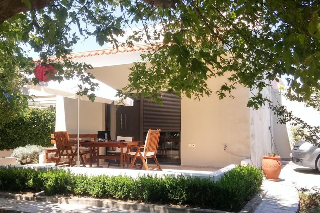 a patio with a table and chairs in front of a house at Melody Birds in Dhíkella