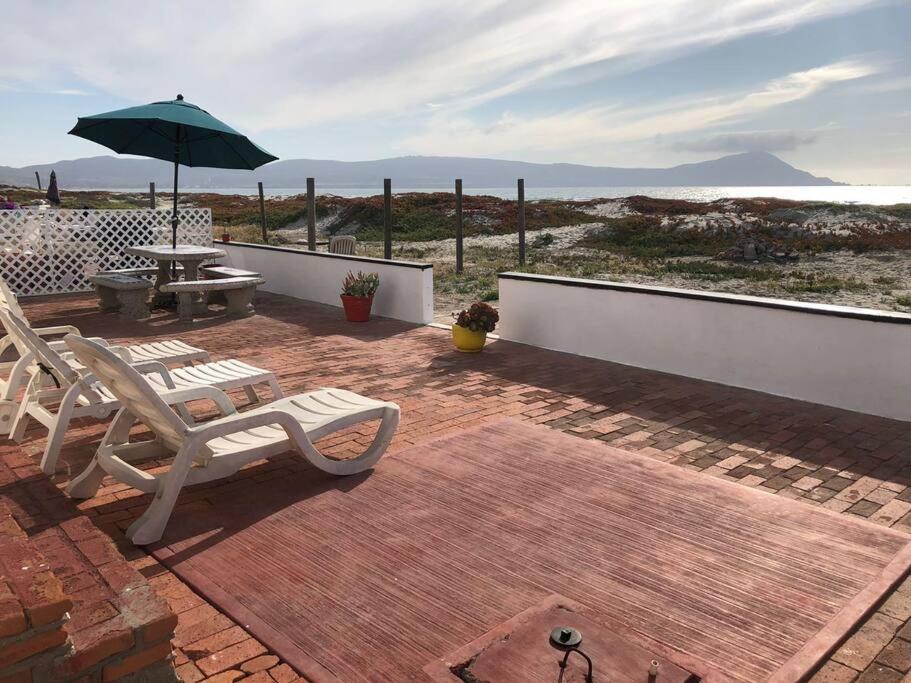 - une terrasse avec 2 chaises, une table et un parasol dans l'établissement Casa Safari frente a la playa, à Ensenada