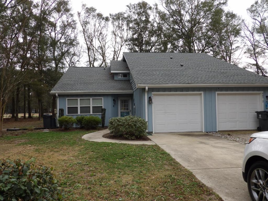 a house with a gray roof and a garage at Bike & Beach Bungalow at Oyster Bay-Sunset Beach in Sunset Beach