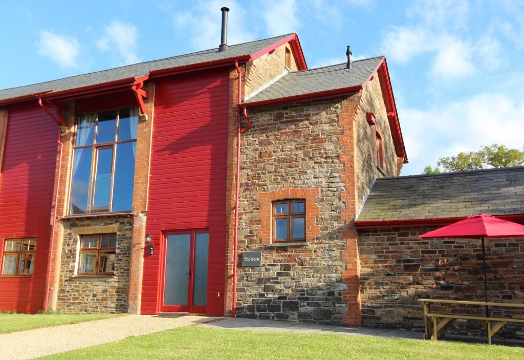 a red brick building with a table and an umbrella at The Barn in Landkey