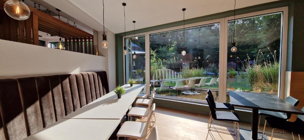 a dining room with a table and chairs and a large window at Utopia Hotel - Art & Nature Hotel in Mons
