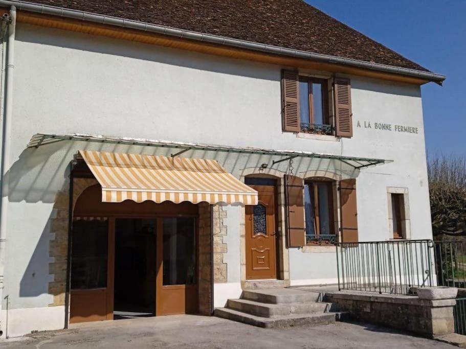 Biały budynek z brązową markizą w obiekcie Gite A la bonne fermière w mieście Nevy-sur-Seille