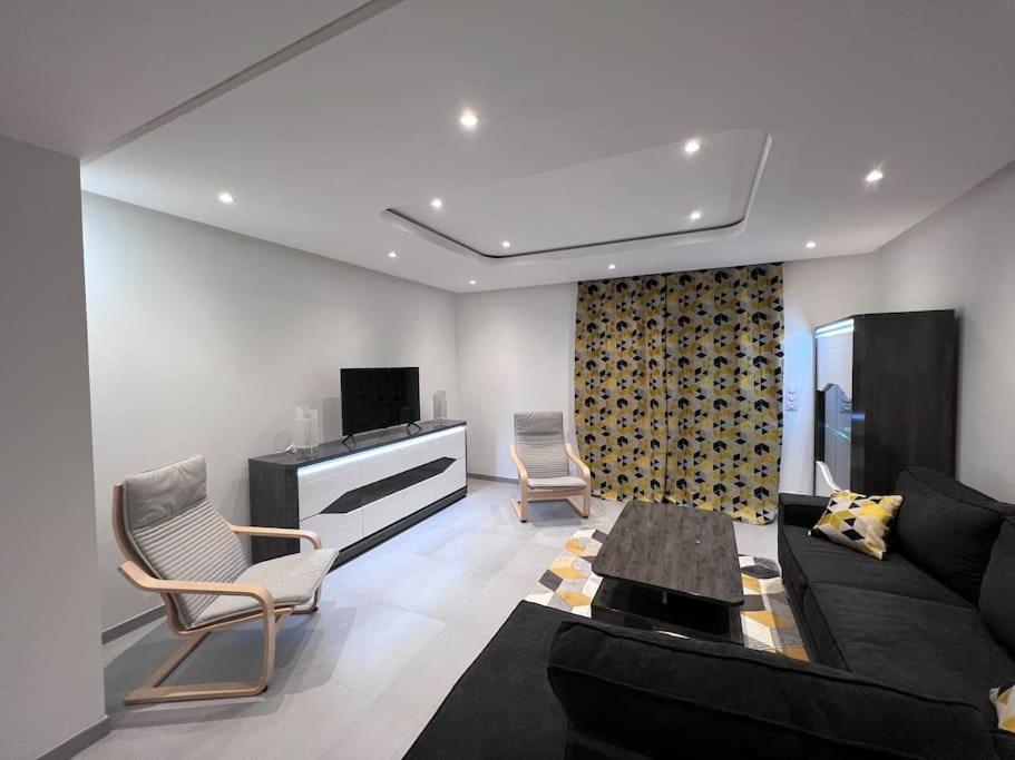 Appartement brest st-marc 6-8personne 2min centre في بريست: غرفة معيشة مع أريكة سوداء وكراسي
