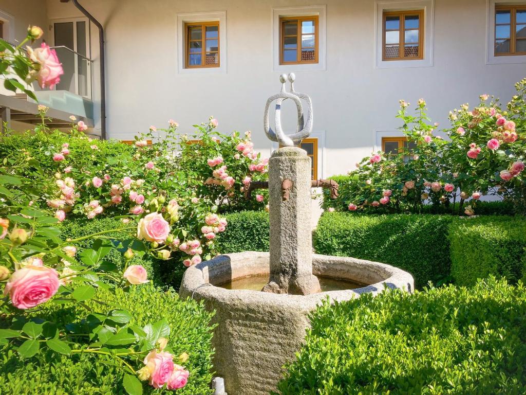 a fountain in a garden with pink roses at Bauernhofpension Herzog zu Laah in Linz