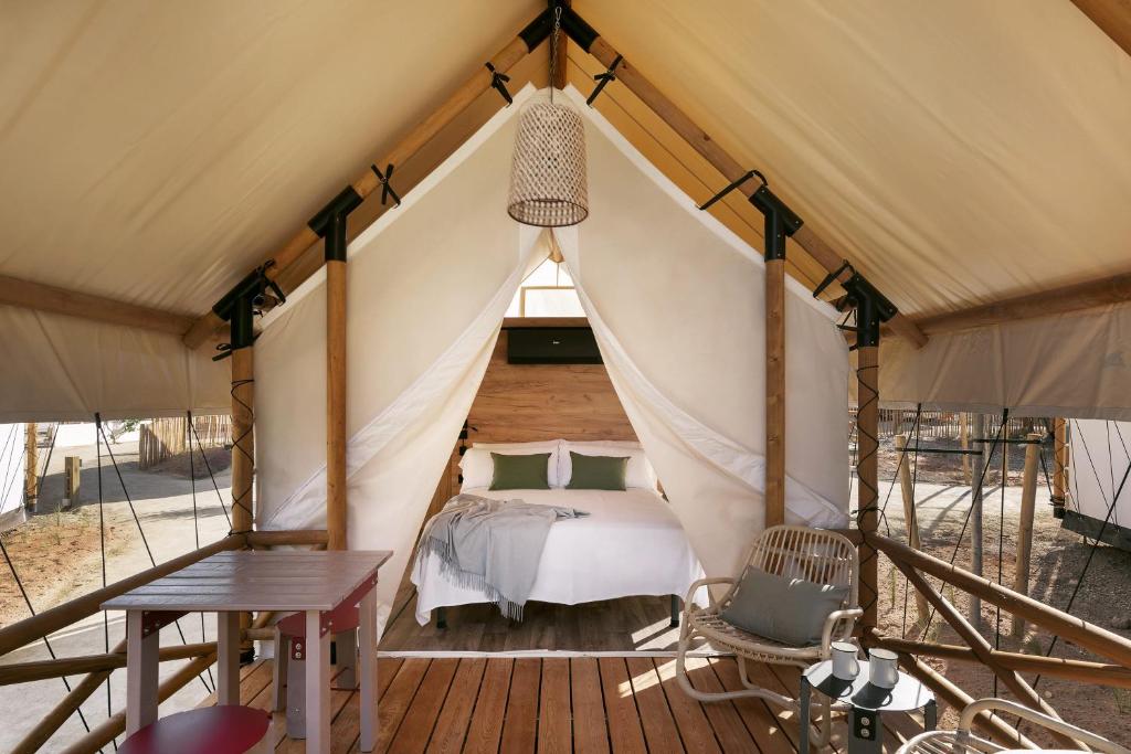 wecamp Cadaqués في كاداكيس: غرفة نوم في خيمة مع سرير وطاولة