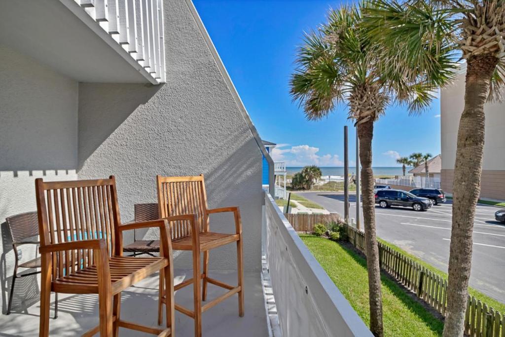 two chairs and a table on a balcony with palm trees at Shore Line Views in Jacksonville Beach