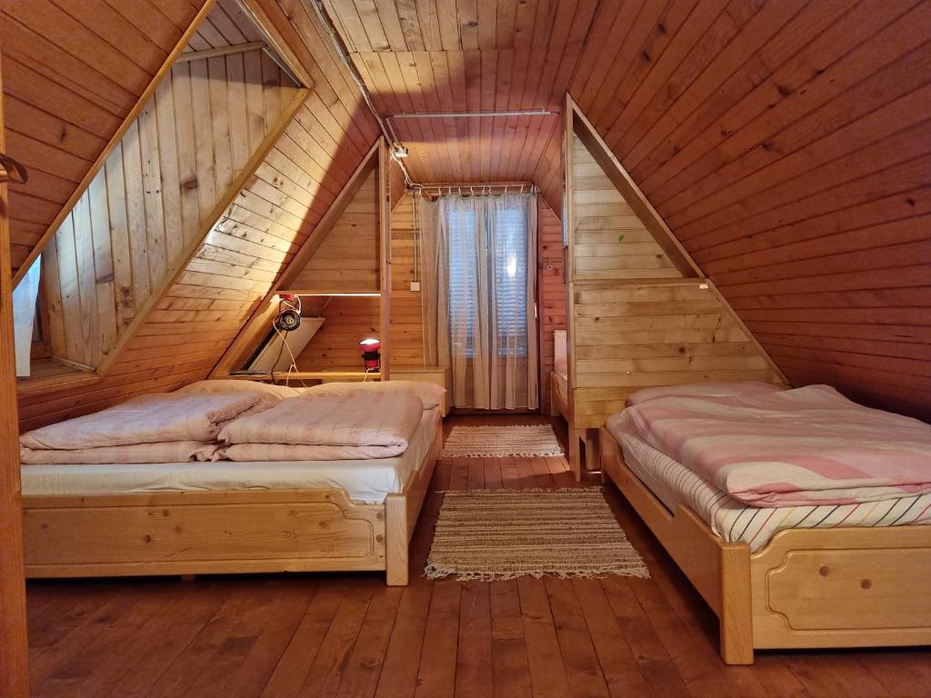 a bedroom with two beds in a wooden attic at Počitniška hiša LIPA in Zreče