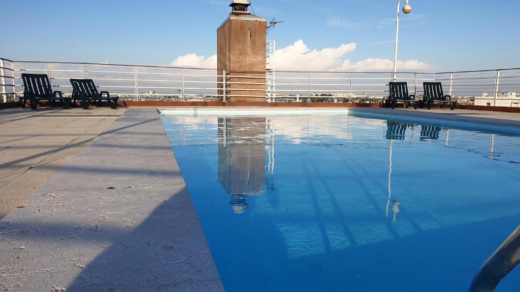 a swimming pool with chairs and a lighthouse in the background at Apart Lisbon Pool Metro Garage in Lisbon