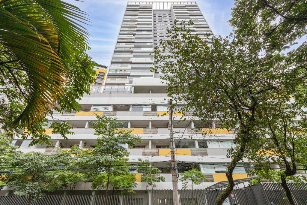 un edificio alto y blanco con árboles delante en ESD - E-Side Vila Madalena - Anora Spaces Residenciais, en São Paulo