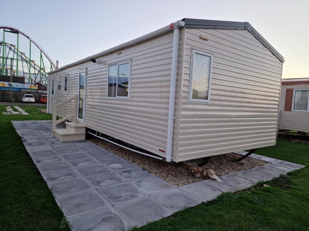a tiny house with a roller coaster in the background at B17 Sunnymede Caravan Park, Fantasy Island, Ingoldmells in Ingoldmells