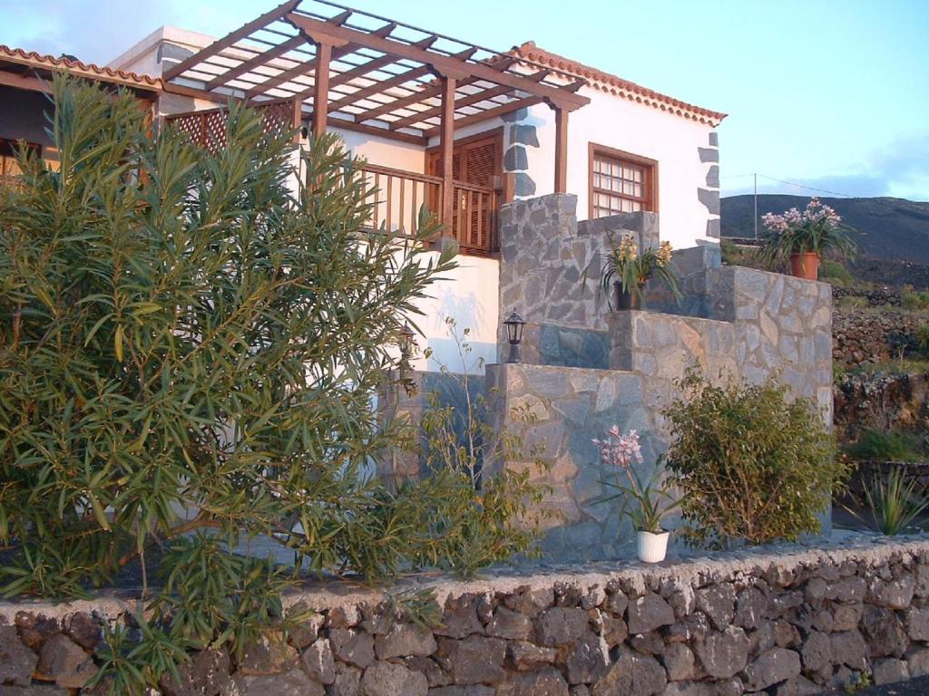 ein Haus mit einer Steinmauer und einigen Pflanzen in der Unterkunft House the Viñas 2 With views of the sea, the mountains and the volcanoes in Fuencaliente de la Palma