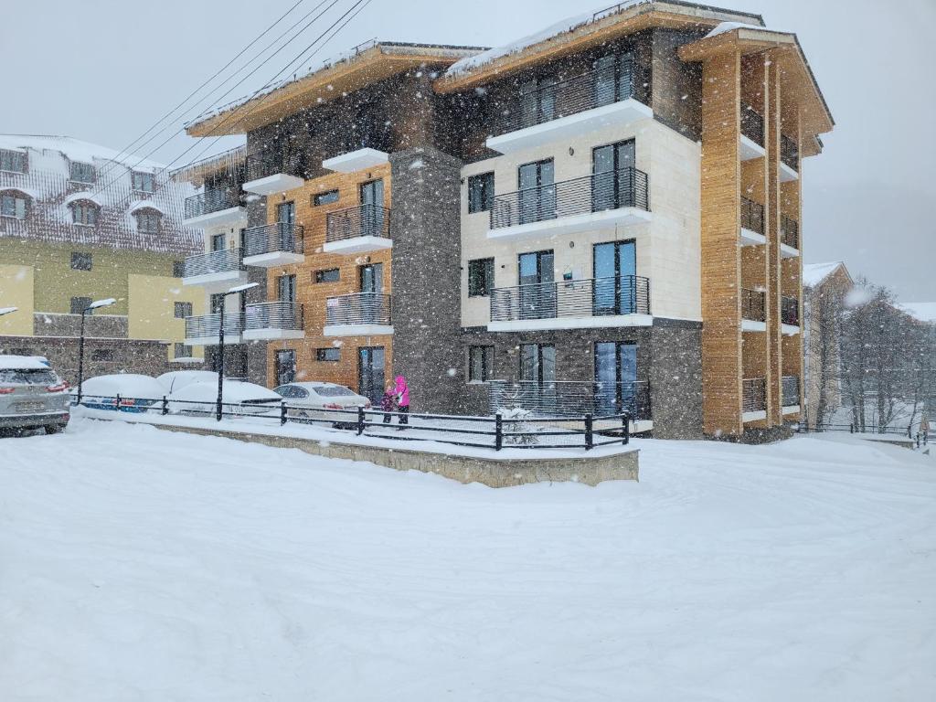 a snow covered parking lot in front of a building at Bakuriani Apt Tatra K2 in Bakuriani