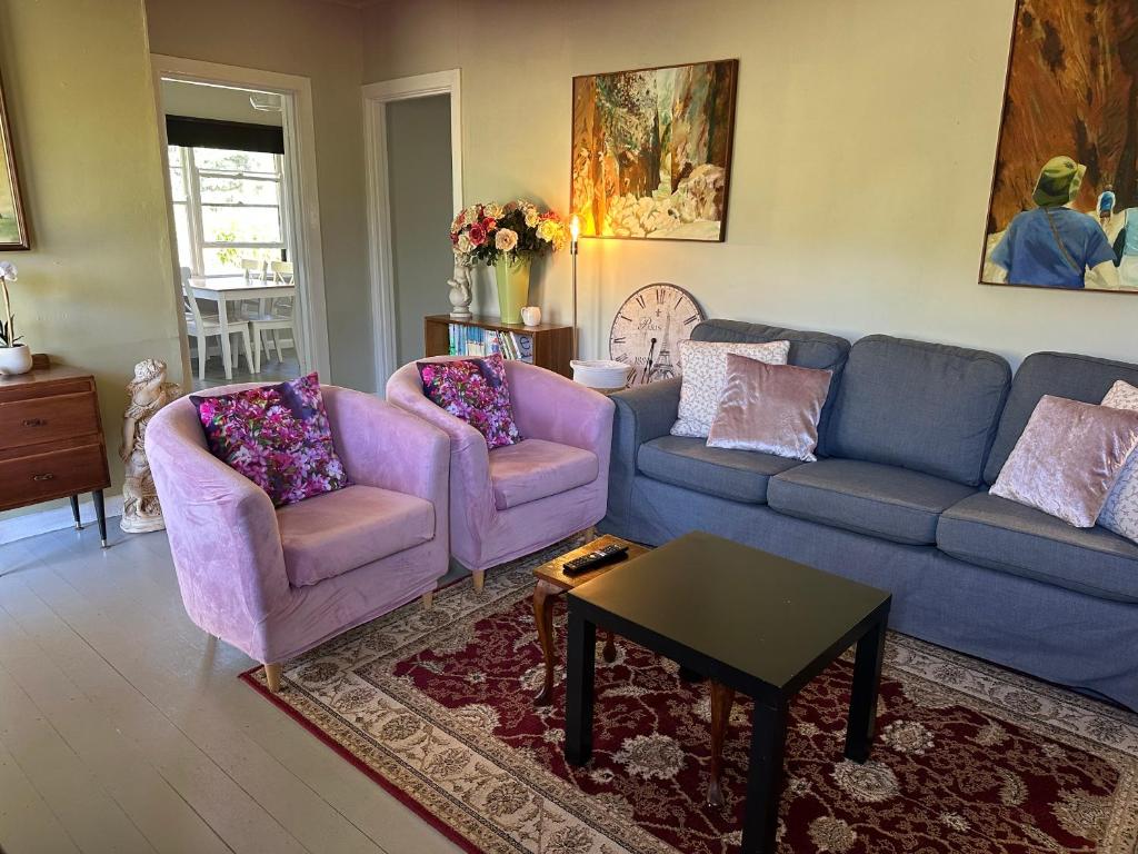 a living room with two couches and a table at Bush Retreat Farm Stay 2 BR in Gelliondale